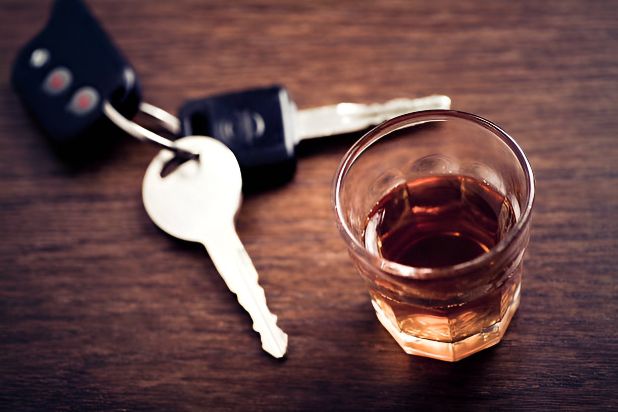 shot glass with alcohol and car keys on a wooden table